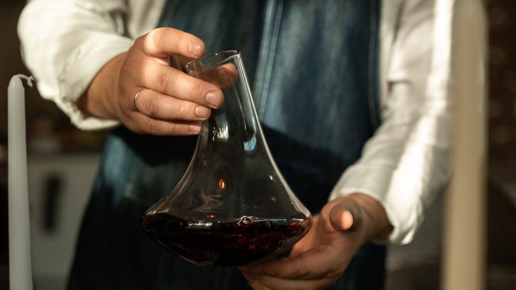 Uomo tiene decanter con vino rosso