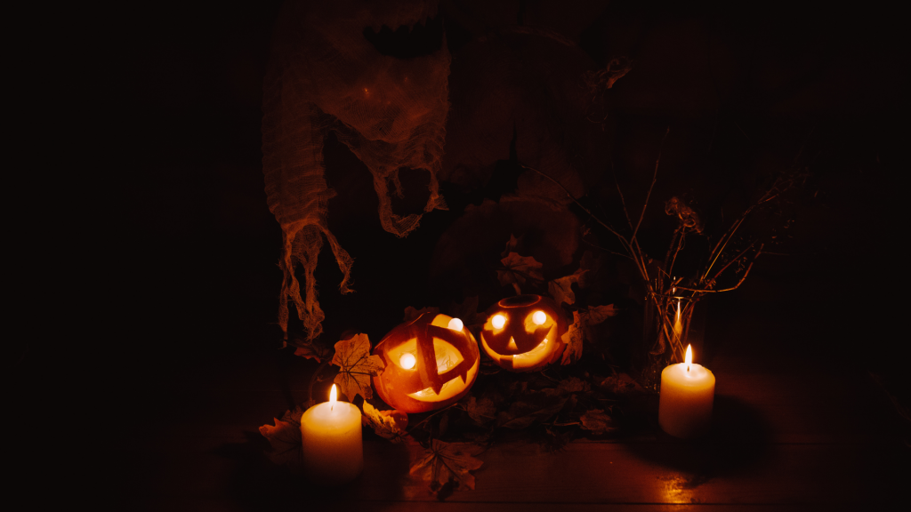 zucche con candele all'interno su sfondo buio, fumo che sale