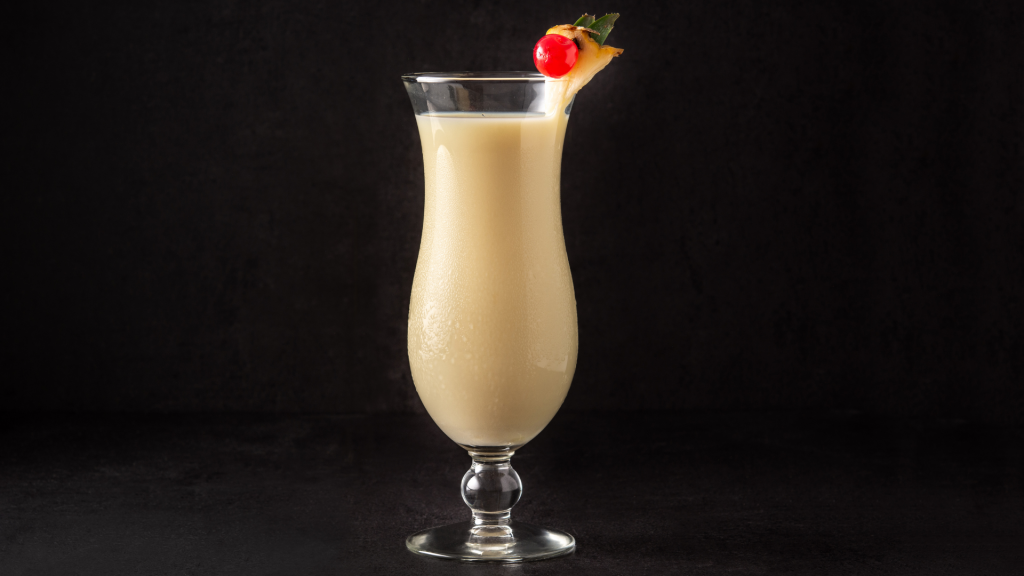 bicchiere di Piña Colada con ananas e ciliegia su sfondo nero