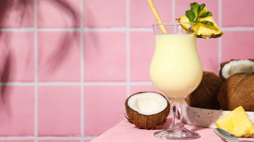 bicchiere di pina colada su sfondo rosa con ananas e cocco di decorazione